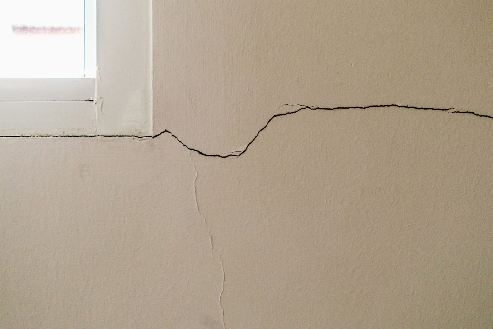 Long settlement crack running across a wall below a window